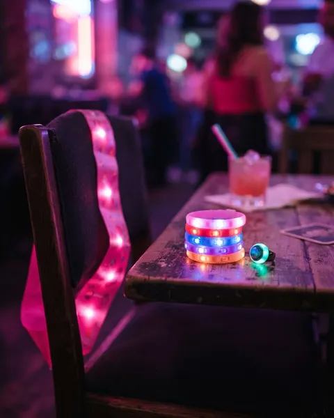 A glowing pink LED party sash with stacked LED bracelets and a color-changing mood ring